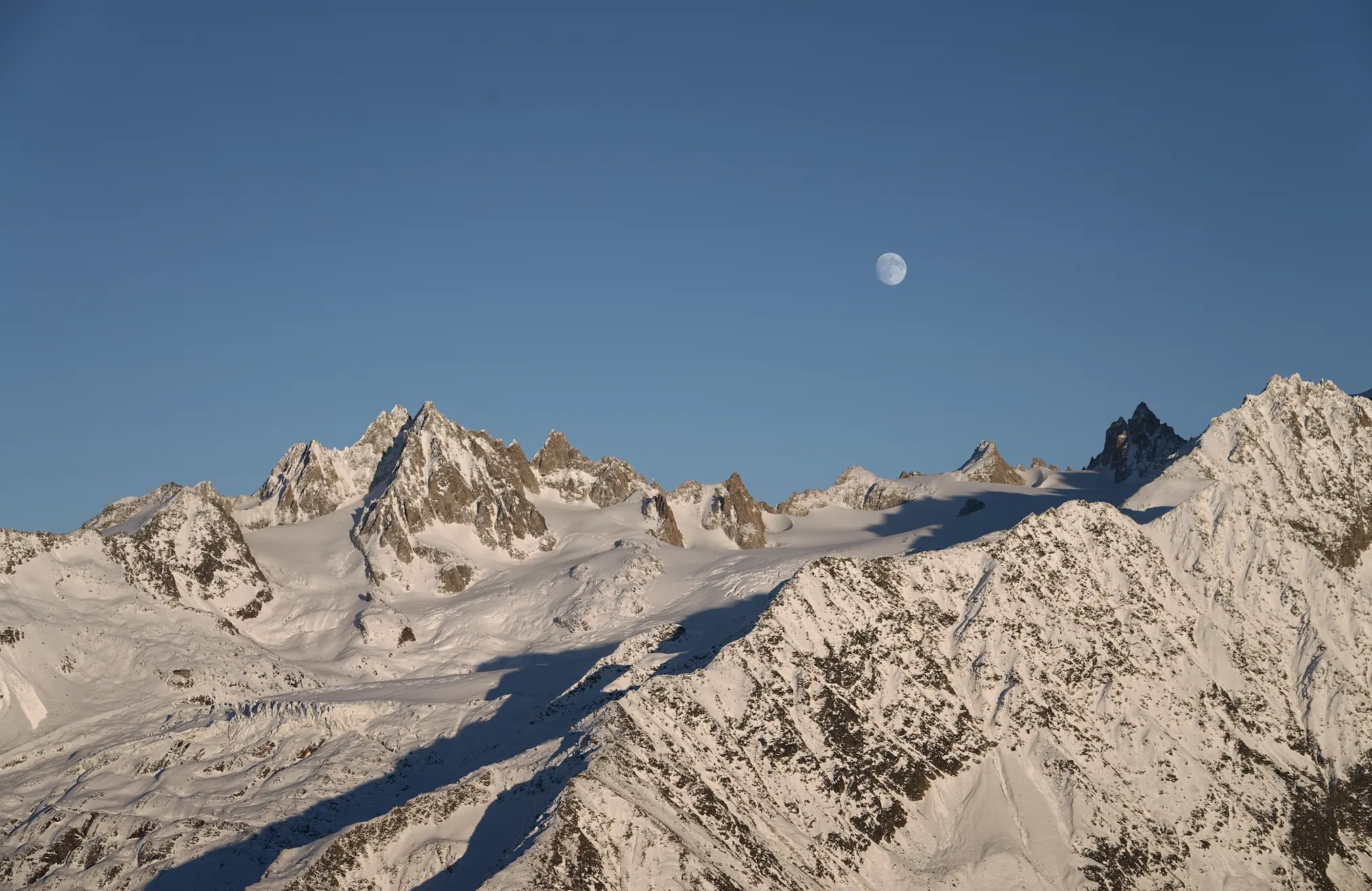 A breathtaking view of Mont Blanc with snow-covered peaks and rocky ridges under a clear blue sky.